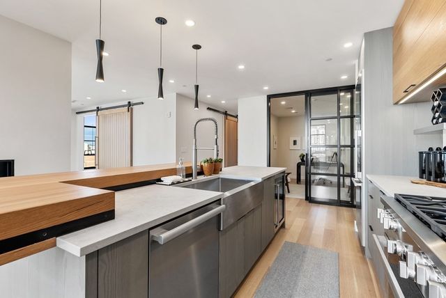 a kitchen with stainless steel appliances granite countertop a sink a stove and a wooden floors