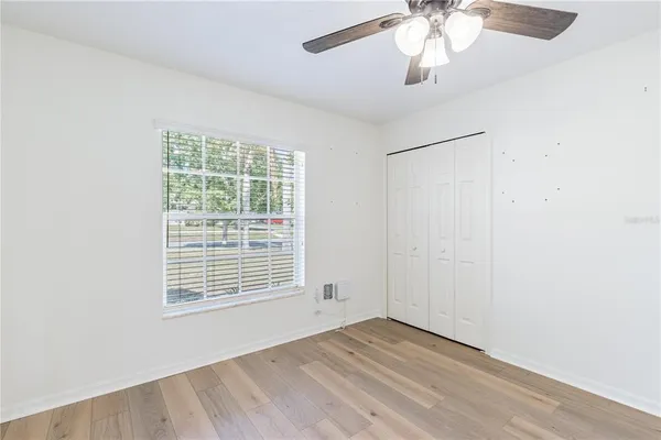 an empty room with wooden floor closet fan and windows