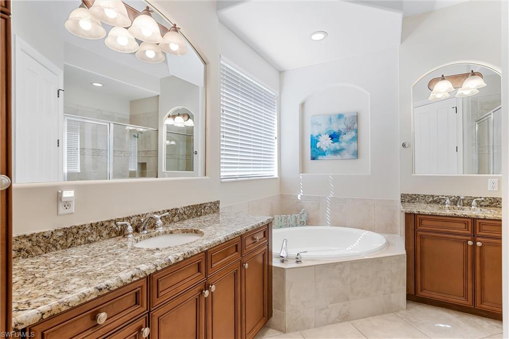 7794 Ashton Road Naples, FL 34113 - Photo 17 of 34 a bathroom with a granite countertop bathtub a sink and a mirror
