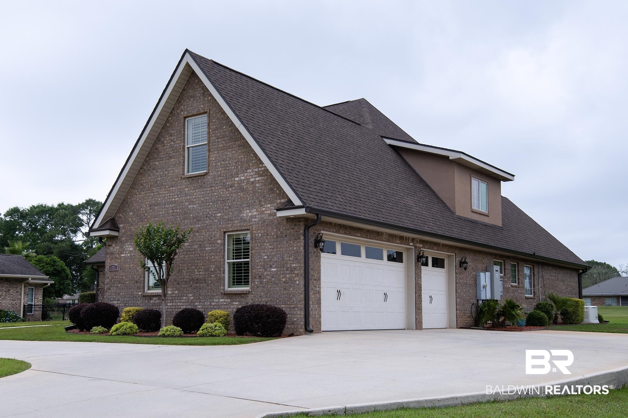 9357 Lakeview Drive Foley, AL 36535 - Photo 2 of 68 Brick exterior with a dormer window, an attached two-car garage, a concrete driveway, and mature landscaping