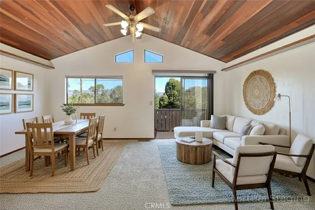 a living room with furniture a chandelier fan and a large window