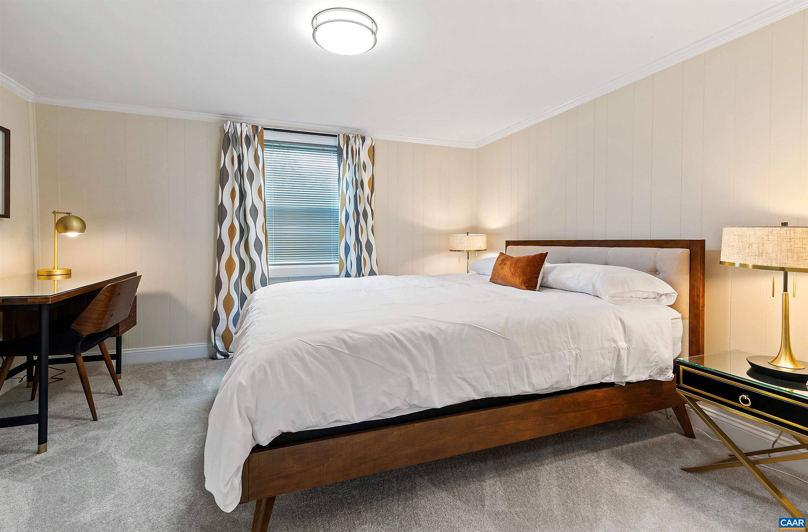 708 West Street Charlottesville, VA 22903 - Photo 27 of 34 a large bed sitting in a bedroom next to a lamp with table and chair