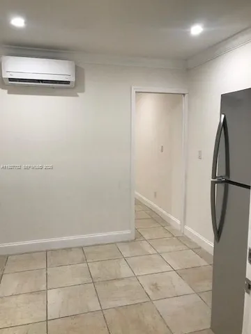 a view of a refrigerator in kitchen and an empty room