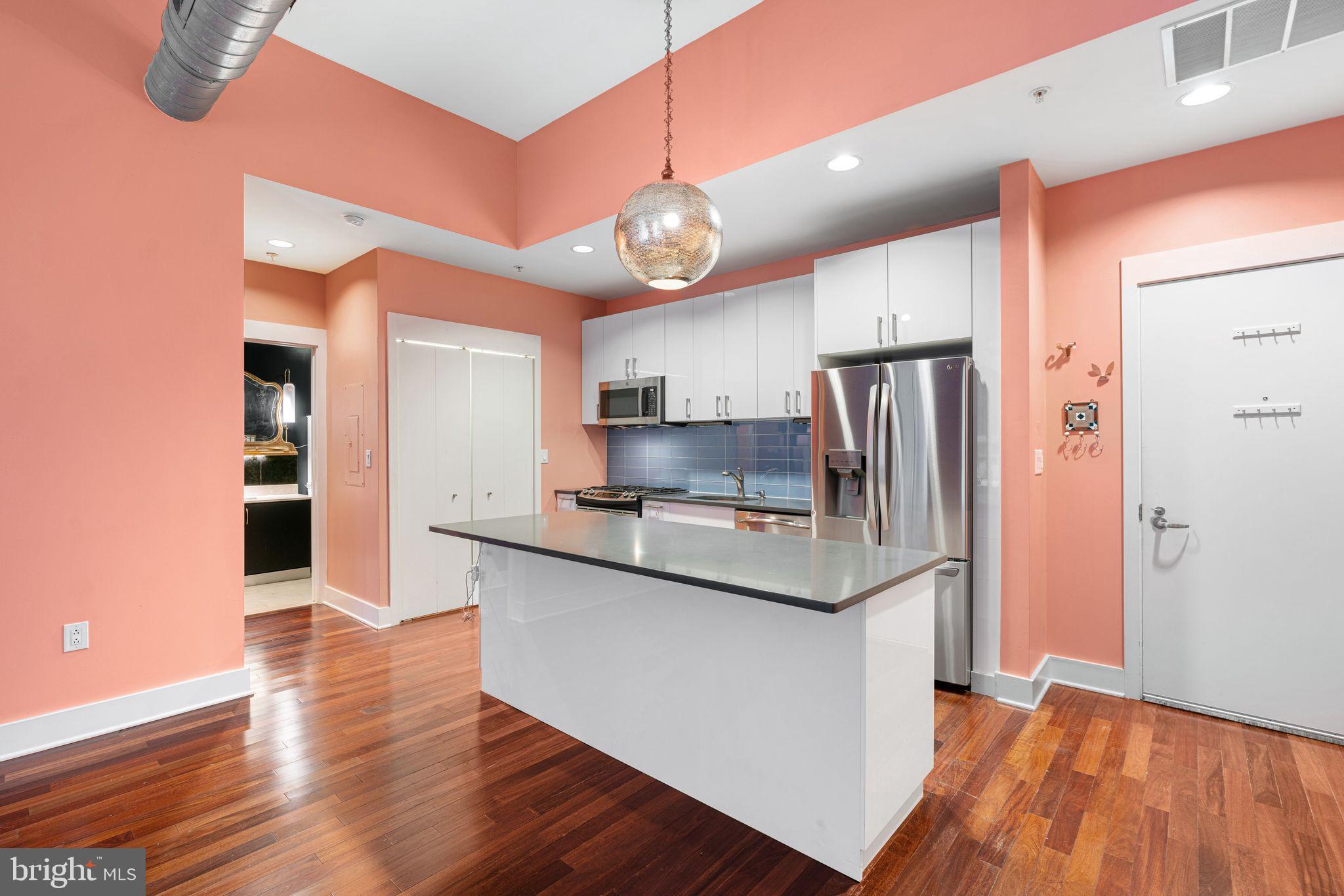1101 Locust Street, Unit 4L Philadelphia, PA 19107 - Photo 6 of 25 a kitchen with stainless steel appliances granite countertop a refrigerator a sink dishwasher a stove and white countertops with wooden floor