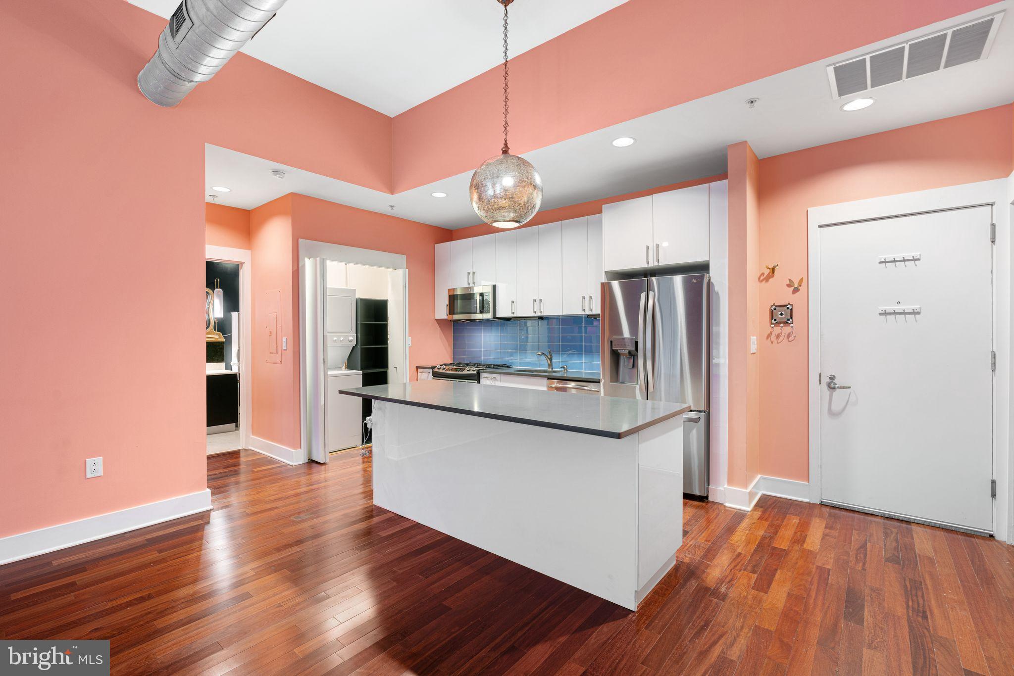 1101 Locust Street, Unit 4L Philadelphia, PA 19107 - Photo 7 of 25 a kitchen with stainless steel appliances granite countertop a refrigerator a sink dishwasher a stove and white countertops with wooden floor