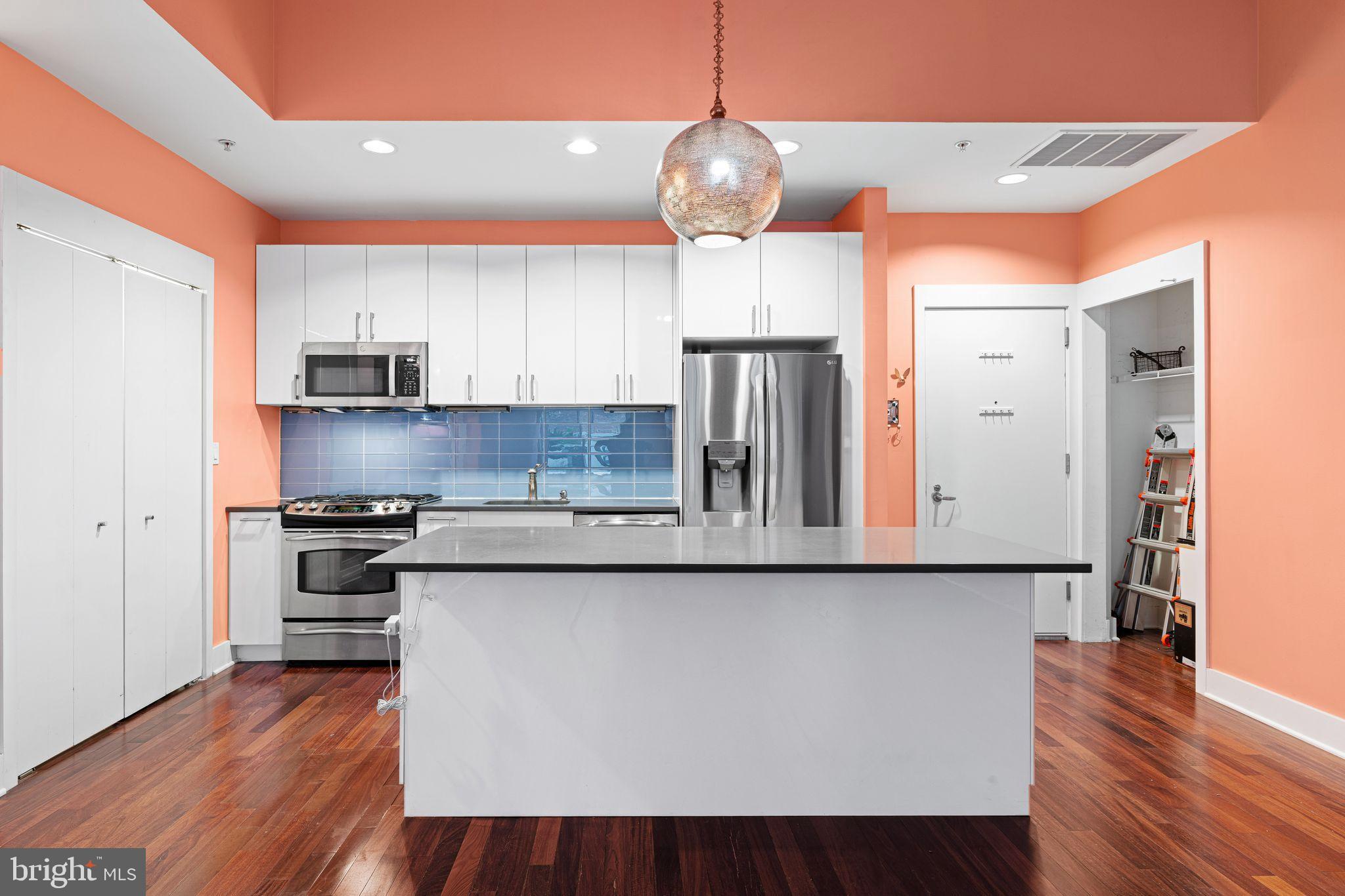 1101 Locust Street, Unit 4L Philadelphia, PA 19107 - Photo 9 of 25 a kitchen with stainless steel appliances granite countertop a refrigerator a stove and a wooden floors