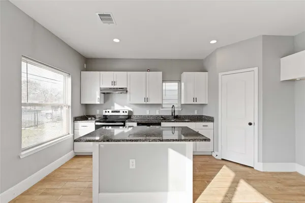 a kitchen with stainless steel appliances granite countertop a stove a sink and a refrigerator