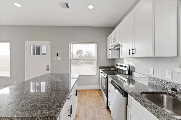 a kitchen with stainless steel appliances granite countertop a sink stove and cabinets