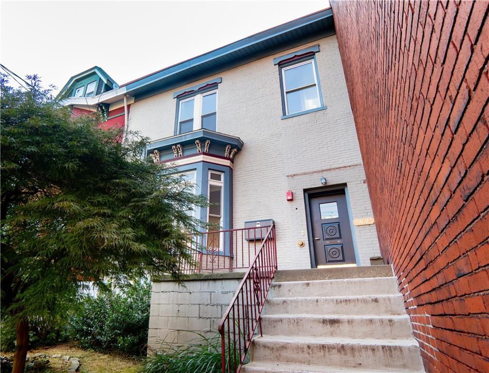 a front view of a house with a tree