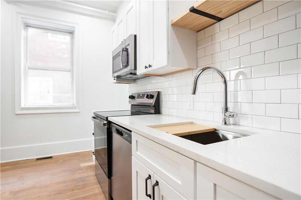4402 Butler Street Pittsburgh, PA 15201 - Photo 10 of 28 a kitchen with stainless steel appliances granite countertop a sink a stove and cabinets