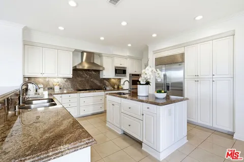 a kitchen with stainless steel appliances granite countertop a stove top oven a sink dishwasher a refrigerator and white cabinets with wooden floor