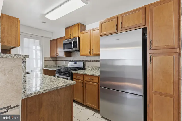 a kitchen with stainless steel appliances granite countertop a refrigerator a stove a sink and a refrigerator