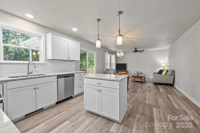 a kitchen with sink stove and white cabinets with wooden floor