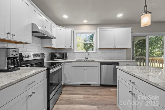 a kitchen with stainless steel appliances granite countertop a sink a stove and a wooden cabinets
