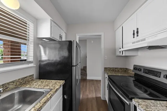 a kitchen with granite countertop a sink stove and refrigerator