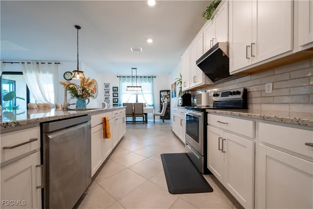 a kitchen with stainless steel appliances kitchen island granite countertop a sink a stove and a microwave