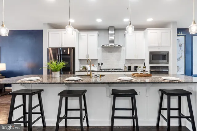 a kitchen with stainless steel appliances granite countertop white cabinets and chairs