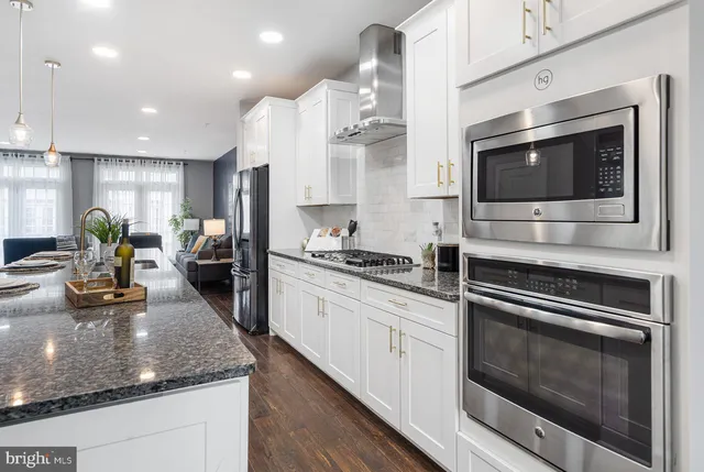 a close view of kitchen with stainless steel appliances granite countertop a refrigerator and a counter top