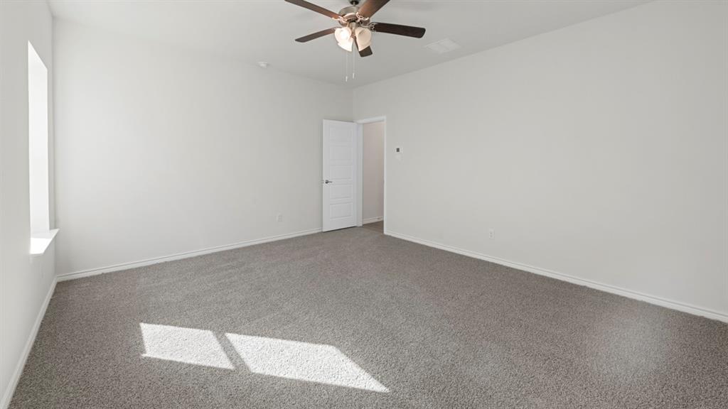 412 Carthage Street Caddo Mills, TX 75135 - Photo 10 of 32 Spacious room featuring gray carpet flooring, white painted walls, a single window, and a ceiling fan with integrated lighting
