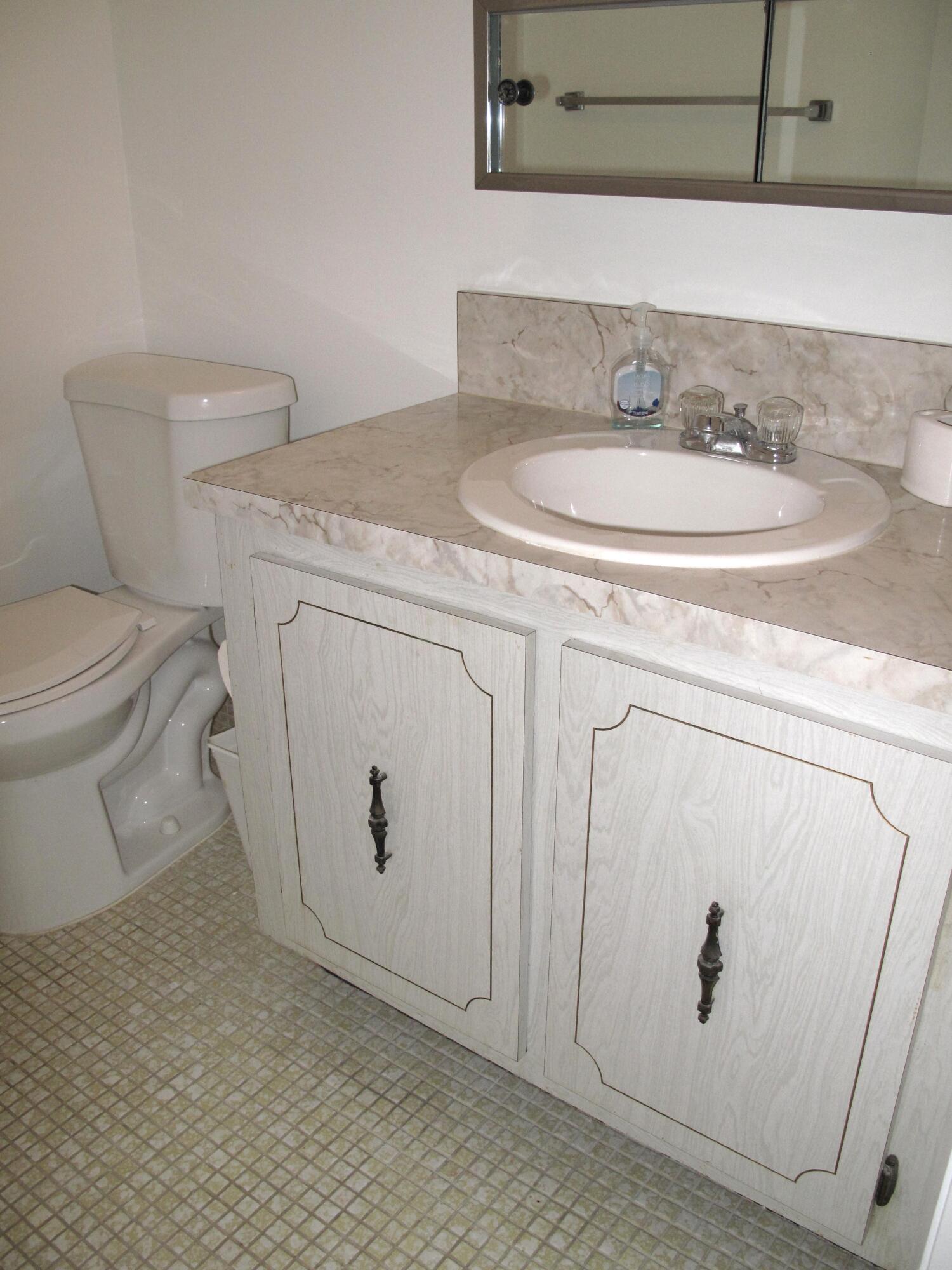 1162 Circle Drive, Unit B Delray Beach, FL 33445 - Photo 11 of 31 a bathroom with a toilet sink and mirror