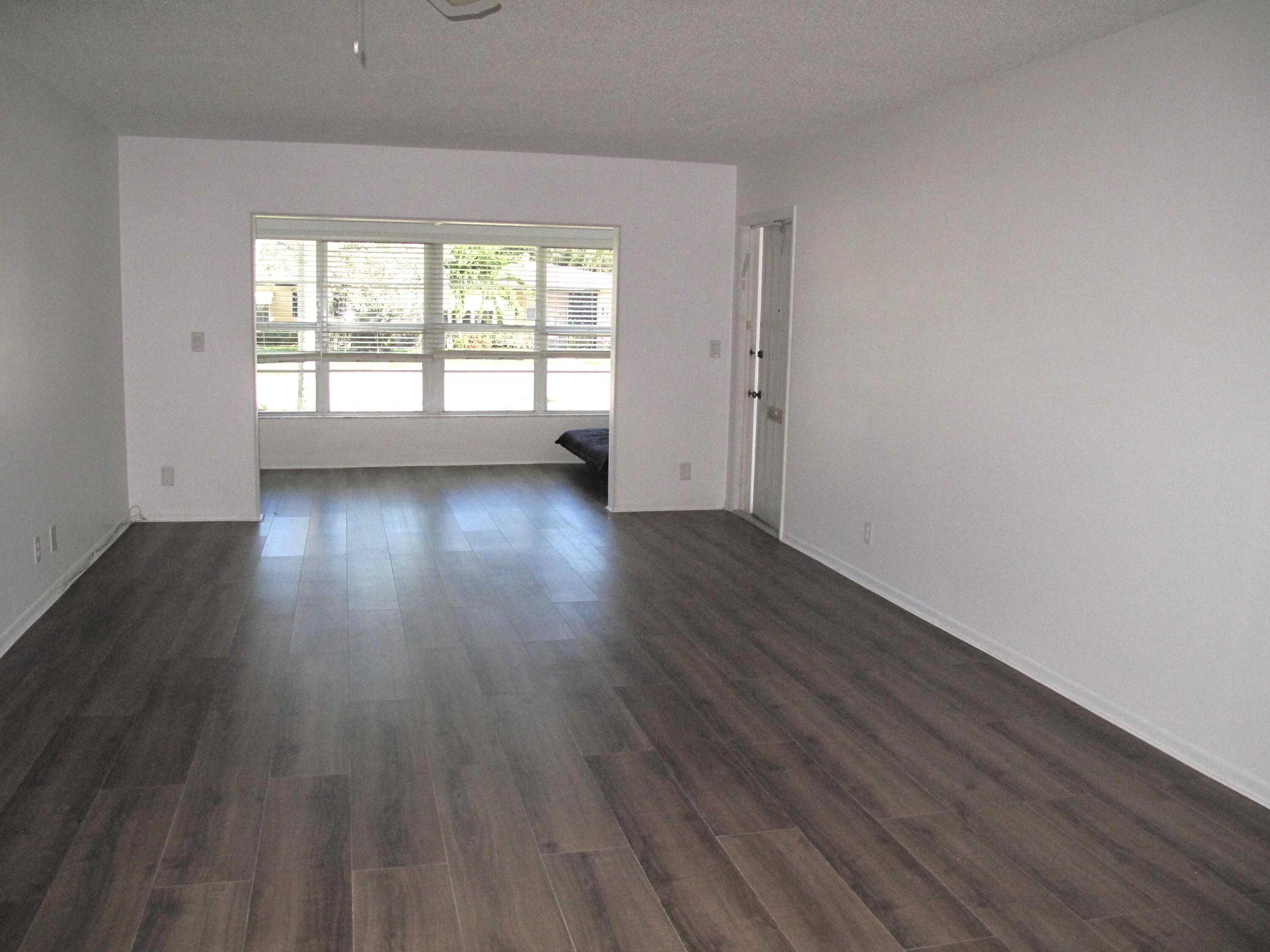 1162 Circle Drive, Unit B Delray Beach, FL 33445 - Photo 9 of 31 an empty room with wooden floor and windows