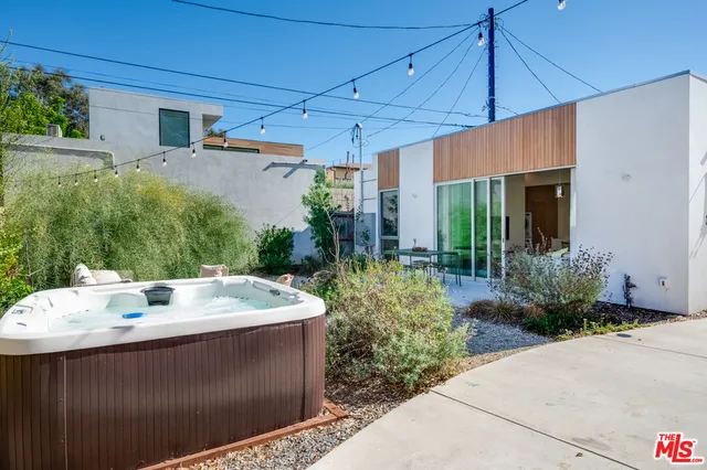 a patio with a table and chairs and potted plants