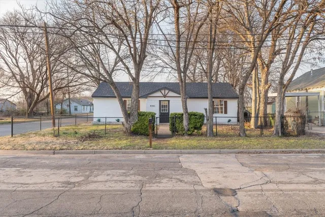 a view of a house with a yard and large trees