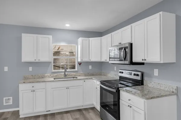 a kitchen with granite countertop white cabinets white stainless steel appliances and sink