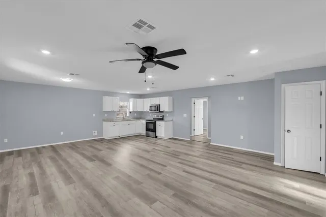a view of a kitchen with wooden floor and a ceiling fan