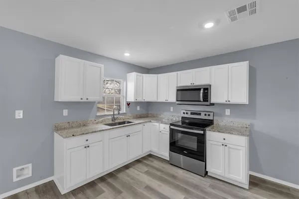 a kitchen with stainless steel appliances granite countertop a sink and white cabinets