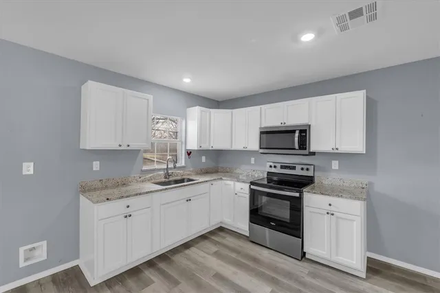 a kitchen with stainless steel appliances granite countertop a sink and white cabinets