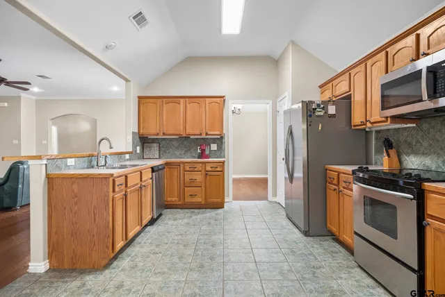 a kitchen with stainless steel appliances granite countertop a stove a sink and a refrigerator