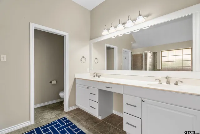 a spacious bathroom with a double vanity sink a large mirror and a shower