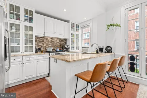 a kitchen with stainless steel appliances granite countertop a table and chairs in it