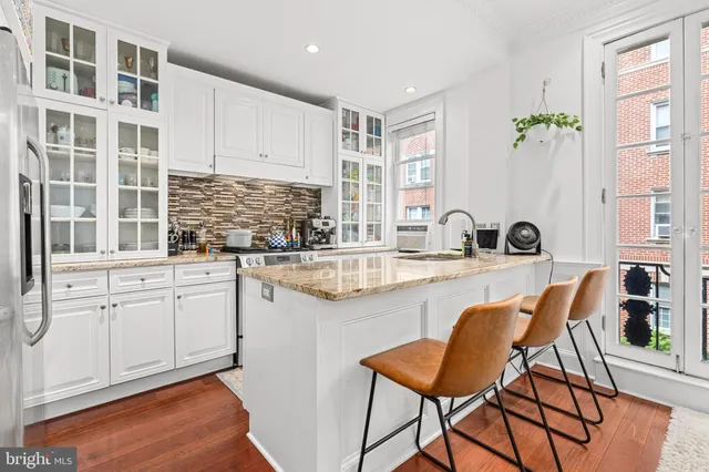 a kitchen with stainless steel appliances granite countertop a table and chairs in it