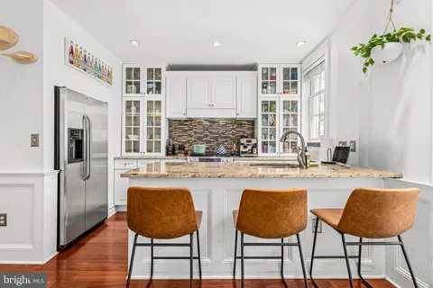 a kitchen with stainless steel appliances granite countertop a table chairs and a refrigerator