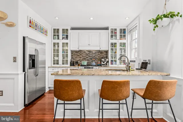 a kitchen with stainless steel appliances granite countertop a table chairs and a refrigerator