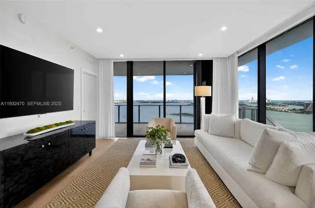 a living room with furniture a flat screen tv and a floor to ceiling window