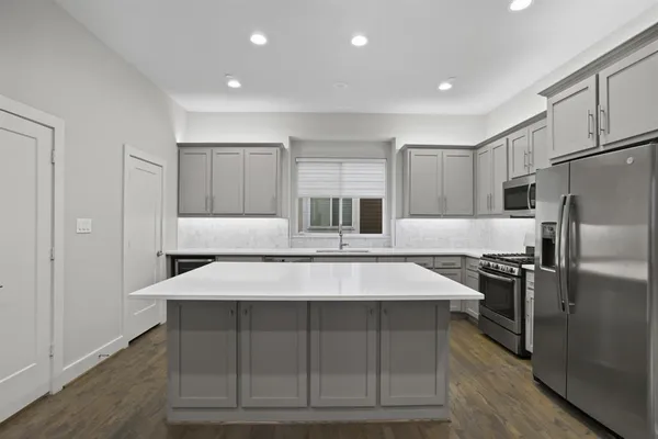 a large kitchen with kitchen island a stove a refrigerator a sink and dishwasher with wooden floor