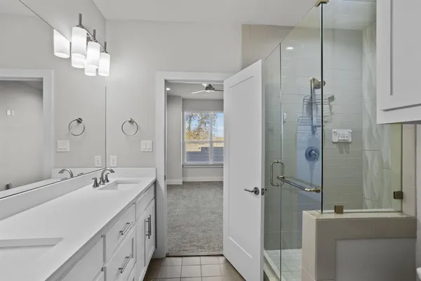 a bathroom with a double vanity sink mirror and shower