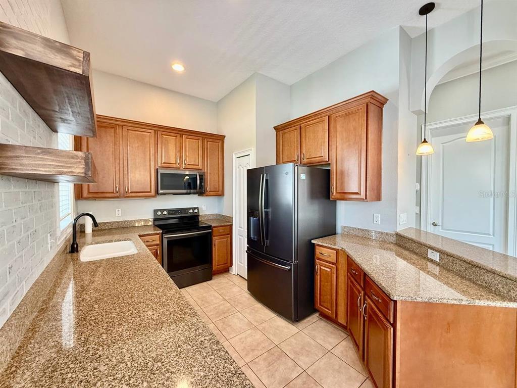 6545 Simone Shores Circle Apollo Beach, FL 33572 - Photo 11 of 46 a kitchen with granite countertop a refrigerator a sink a stove a microwave and island