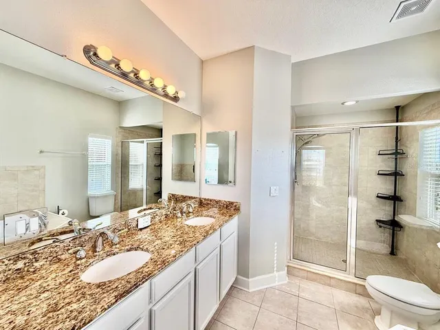 a bathroom with a granite countertop sink mirror vanity and toilet