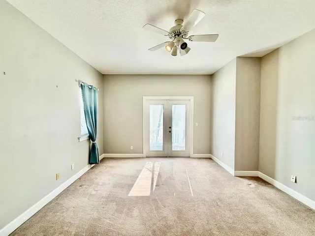 an empty room with a ceiling fan and window