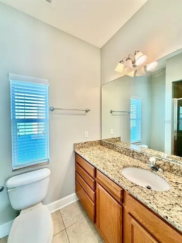 a bathroom with a granite countertop sink a toilet and a mirror