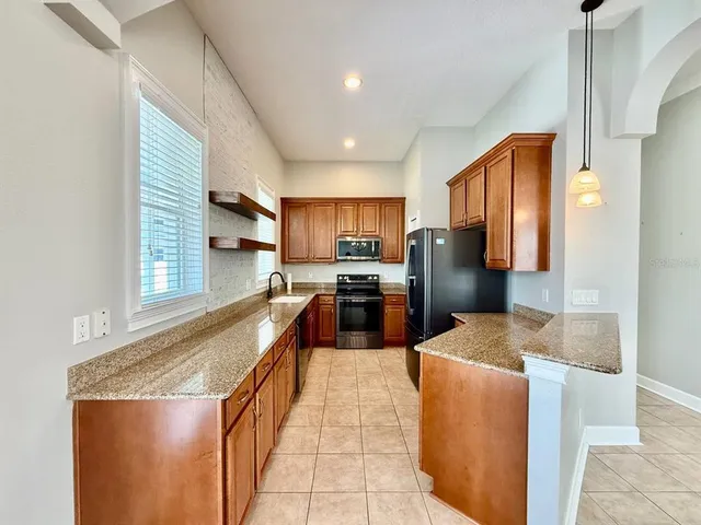 a kitchen with stainless steel appliances granite countertop wooden cabinets a sink and a stove