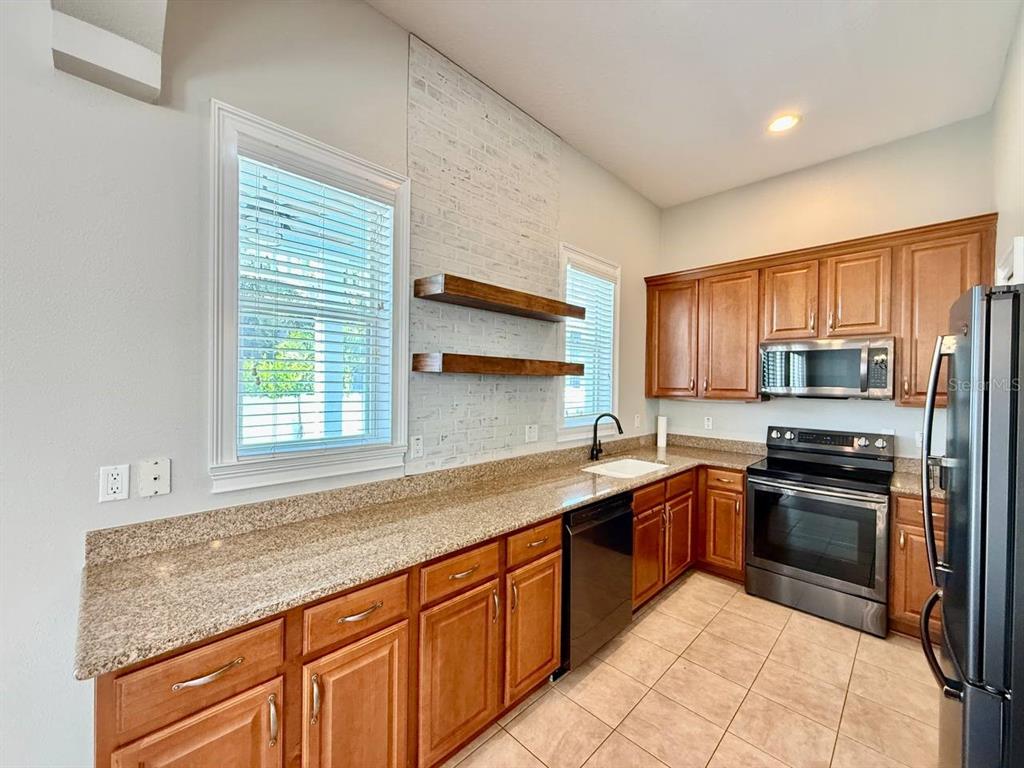 6545 Simone Shores Circle Apollo Beach, FL 33572 - Photo 10 of 46 a kitchen with stainless steel appliances granite countertop a sink and stove top oven