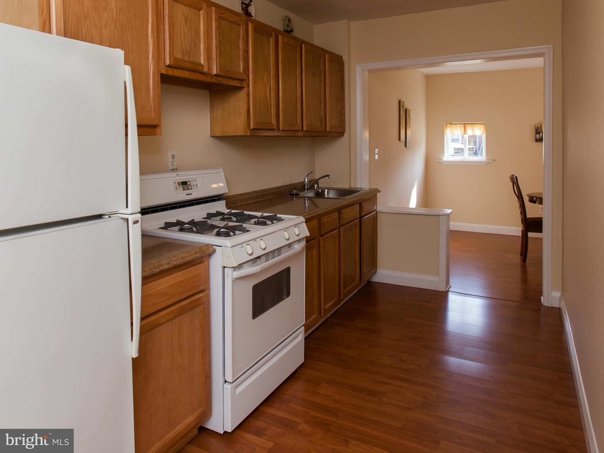 2962 Cornwall Road Dundalk, MD 21222 - Photo 6 of 28 a kitchen with granite countertop wooden floors and white stainless steel appliances