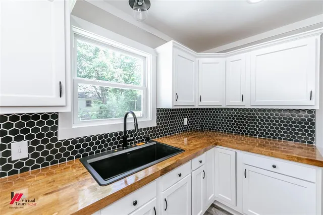 a kitchen with granite countertop a sink and a white cabinets