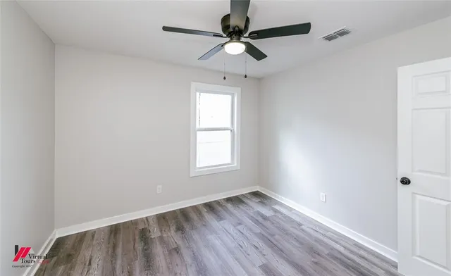 an empty room with a window and a ceiling fan