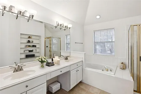 a bathroom with a sink double vanity granite tub shower and a mirror